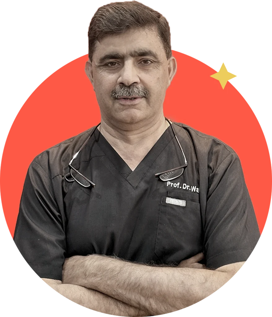 A middle-aged man with dark hair and a mustache, wearing black medical scrubs, stands with his arms crossed. He is framed in a circular, orange-red graphic with a small yellow star in the upper right.