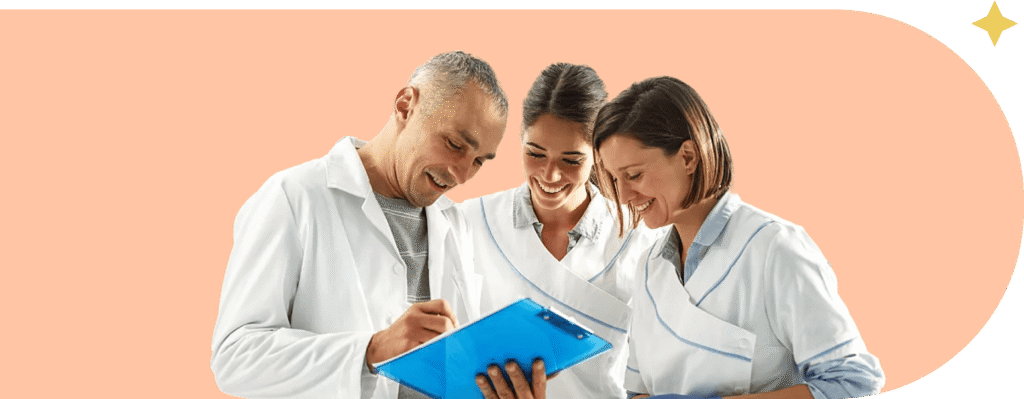 A team of three medical or lab professionals—a man and two women, all wearing white lab coats—are gathered closely together, intently reviewing notes on a blue clipboard. They are standing against a solid peach-colored background.